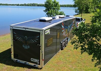 CORE RV 8032 model shown aside a lake with solar panels and a custom eagle wrap with an American flag