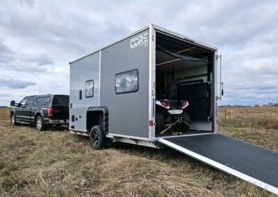 An exterior shot of a CORE RV 8016 toy hauler with the ramp door down and a four-wheeler mounted inside