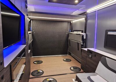 Interior view of CORE RV toy hauler showing the loadable space with the dinette seats folded upward, a highlight of the interior RGB lights in a blue